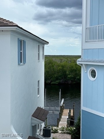 5825 Shell Cove Dr Unit 115, Cape Coral, FL 33914 - view of property exterior featuring a dock, a water view, stucco siding, and central air condition unit