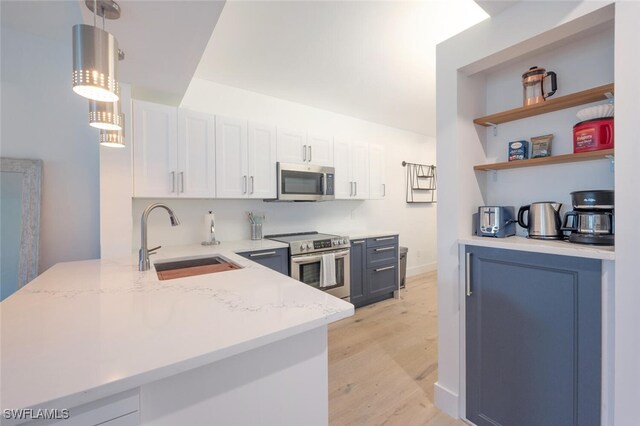 kitchen featuring pendant lighting, sink, light wood-type flooring, appliances with stainless steel finishes, and white cabinetry