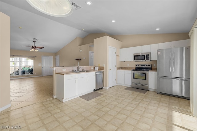 kitchen featuring stainless steel appliances, sink, ceiling fan, vaulted ceiling, and white cabinets