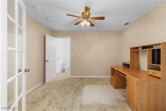 unfurnished office featuring built in desk, ceiling fan, and light colored carpet