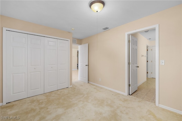 unfurnished bedroom featuring light carpet and a closet