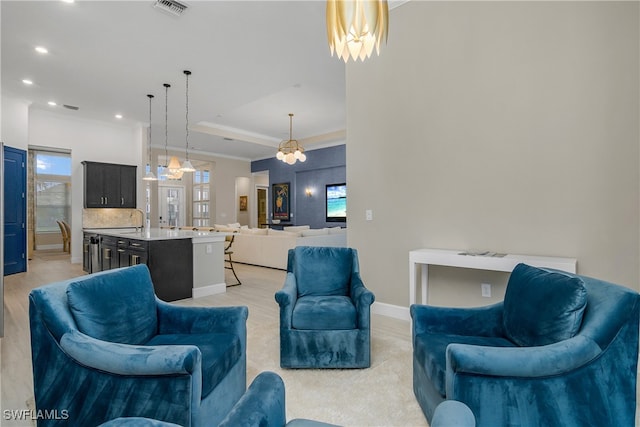 living room featuring sink, plenty of natural light, a tray ceiling, and a chandelier