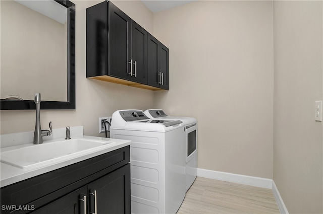 washroom with sink, light hardwood / wood-style floors, cabinets, and independent washer and dryer