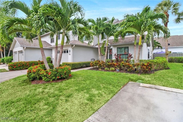 view of front of home featuring stucco siding, a shingled roof, a front yard, and fence