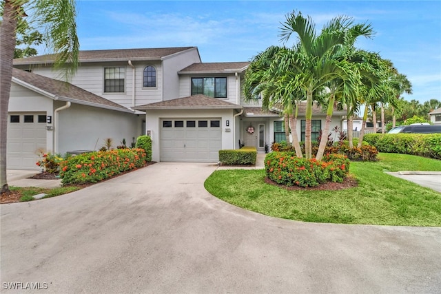 view of front of property featuring a front lawn, a garage, driveway, and stucco siding