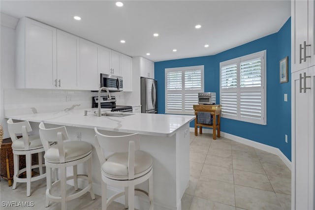 kitchen with appliances with stainless steel finishes, light tile patterned flooring, kitchen peninsula, and backsplash