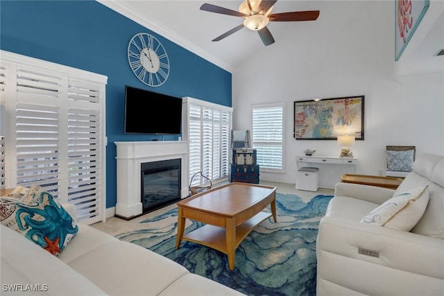 living room featuring a glass covered fireplace, crown molding, high vaulted ceiling, and ceiling fan