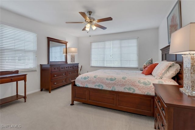 bedroom featuring multiple windows, a ceiling fan, baseboards, and light carpet