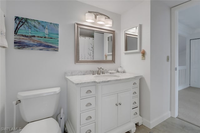 bathroom with toilet, vanity, and baseboards