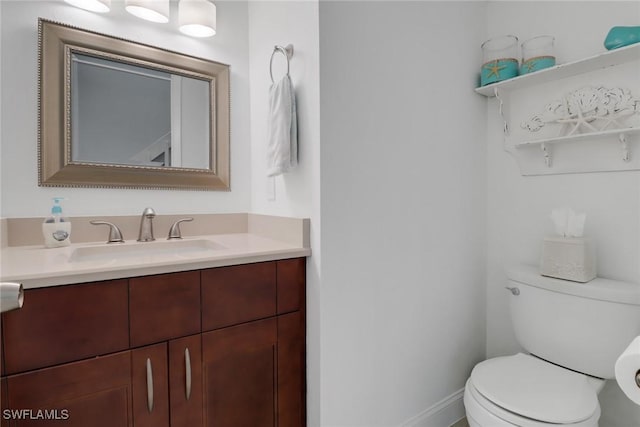 bathroom with toilet, vanity, and baseboards