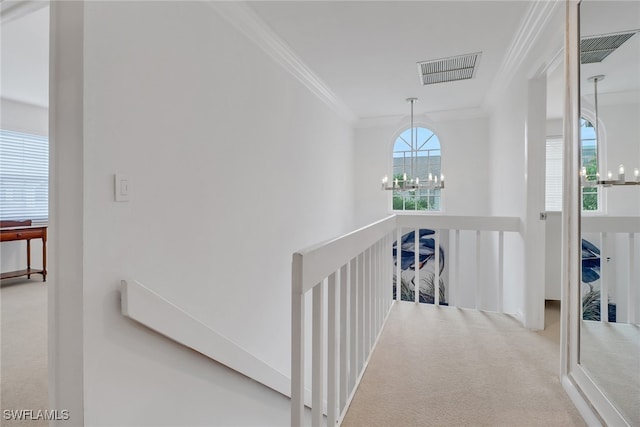 hallway featuring visible vents, an inviting chandelier, crown molding, carpet flooring, and an upstairs landing