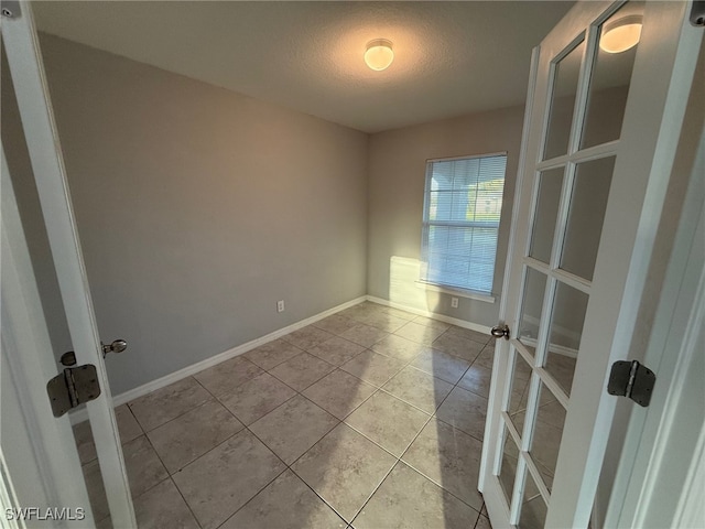 tiled empty room with a textured ceiling and french doors