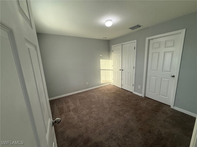 unfurnished bedroom with a closet and dark colored carpet