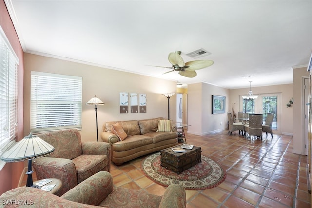 living room featuring tile patterned flooring, crown molding, and ceiling fan with notable chandelier