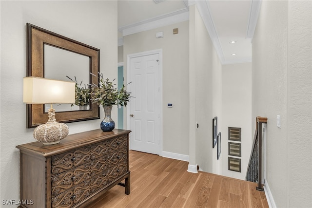 hallway with light wood-type flooring and crown molding