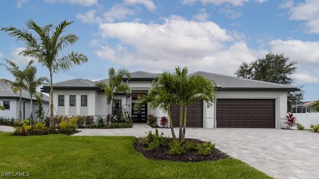 view of front of property featuring a front yard, decorative driveway, an attached garage, and stucco siding