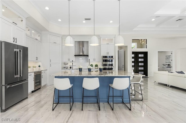 kitchen with wall chimney range hood, appliances with stainless steel finishes, decorative light fixtures, white cabinetry, and beverage cooler