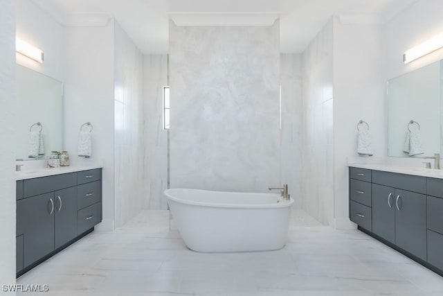 full bathroom with marble finish floor, tile walls, two vanities, a freestanding tub, and walk in shower