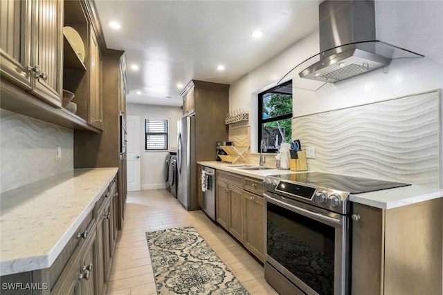 kitchen with tasteful backsplash, separate washer and dryer, light wood-type flooring, island exhaust hood, and stainless steel appliances