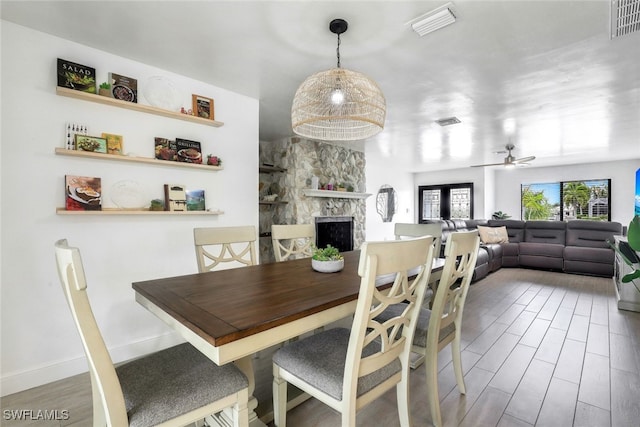 dining space featuring a stone fireplace, hardwood / wood-style flooring, and ceiling fan