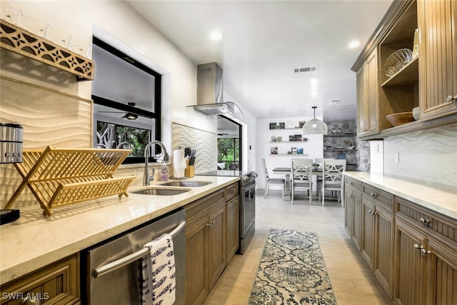 kitchen featuring dishwasher, wall chimney exhaust hood, light hardwood / wood-style flooring, hanging light fixtures, and sink