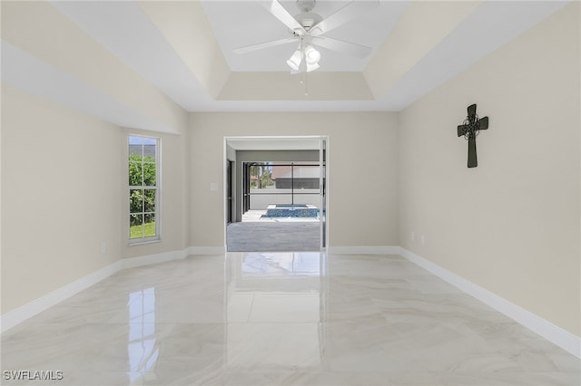 empty room featuring a raised ceiling and ceiling fan