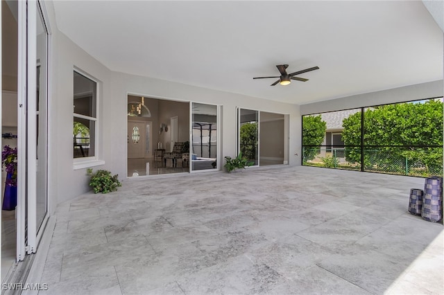 unfurnished sunroom featuring ceiling fan with notable chandelier