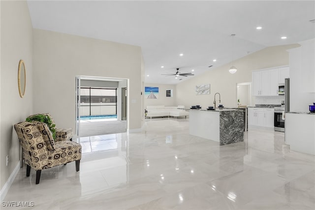 kitchen with white cabinetry, ceiling fan, hanging light fixtures, stainless steel appliances, and a kitchen island with sink