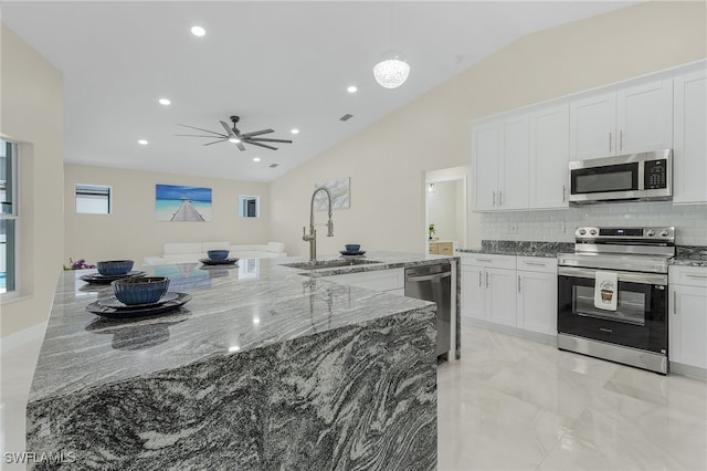 kitchen with stainless steel appliances, sink, stone countertops, white cabinets, and lofted ceiling