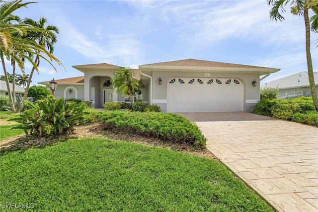 view of front of house featuring a garage, a front lawn, decorative driveway, and stucco siding