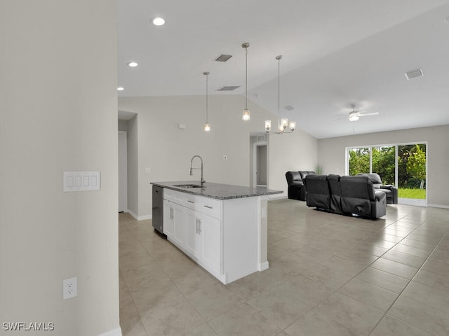 kitchen featuring white cabinetry, sink, lofted ceiling, dark stone counters, and hanging light fixtures