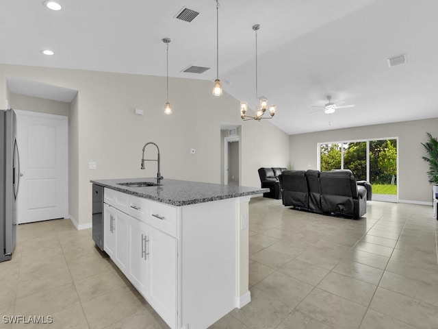 kitchen featuring vaulted ceiling, light tile patterned floors, sink, dark stone countertops, and a center island with sink