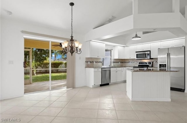 kitchen featuring backsplash, white cabinets, light tile patterned floors, decorative light fixtures, and stainless steel appliances