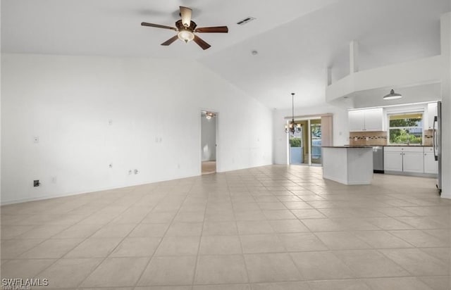 unfurnished living room with ceiling fan with notable chandelier, high vaulted ceiling, and light tile patterned flooring