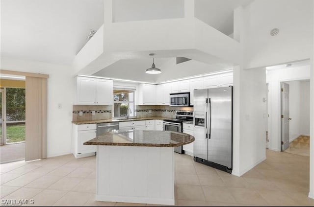 kitchen with light tile patterned flooring, backsplash, a towering ceiling, white cabinetry, and stainless steel appliances