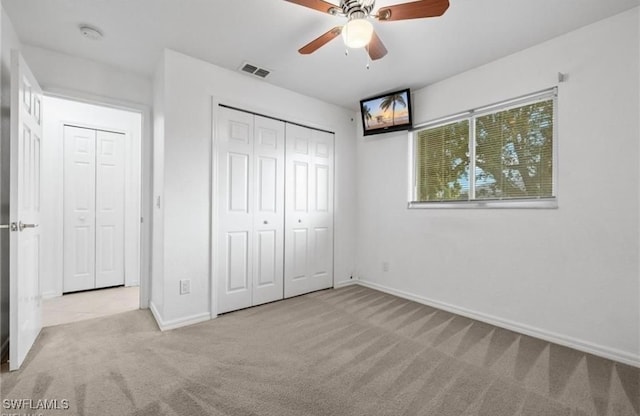 unfurnished bedroom with ceiling fan, light colored carpet, and a closet