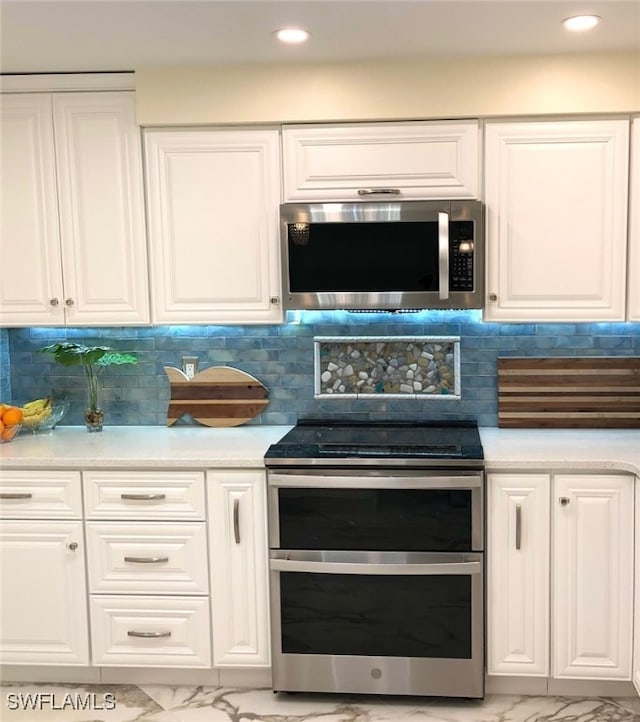 kitchen with light tile patterned floors, appliances with stainless steel finishes, decorative backsplash, and white cabinets