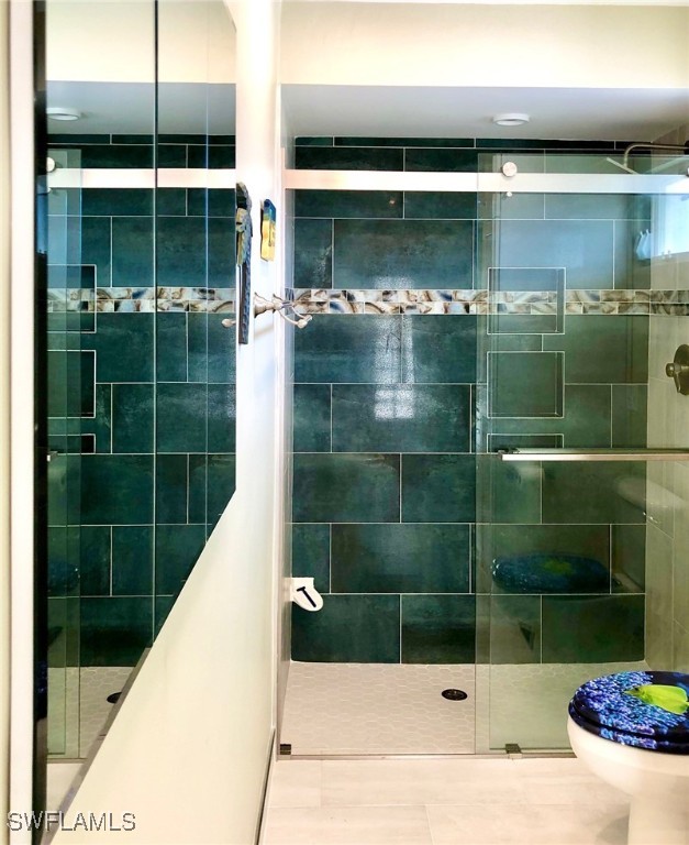 bathroom with tile patterned floors, an enclosed shower, and toilet