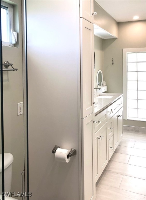 bathroom with toilet, vanity, and a healthy amount of sunlight