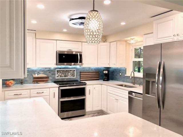 kitchen with decorative backsplash, pendant lighting, white cabinets, sink, and stainless steel appliances