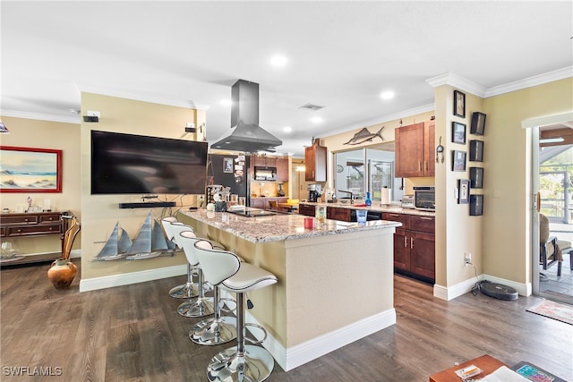 kitchen featuring a kitchen island with sink, a kitchen bar, light stone countertops, dark wood-type flooring, and island exhaust hood