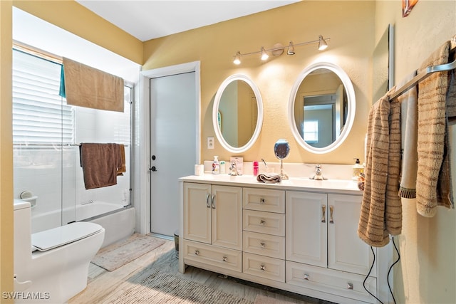 full bathroom featuring vanity, toilet, hardwood / wood-style floors, and bath / shower combo with glass door