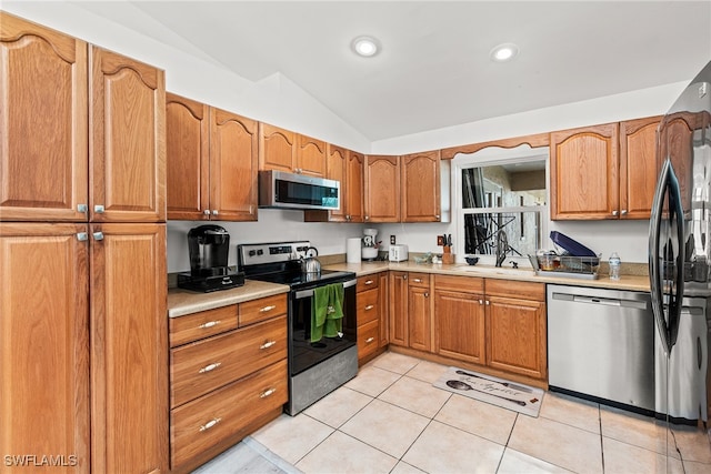 kitchen with sink, light tile patterned flooring, stainless steel appliances, and vaulted ceiling