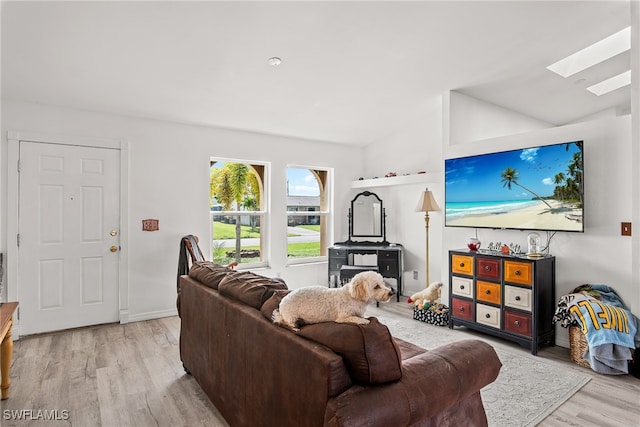 living room with vaulted ceiling with skylight and light hardwood / wood-style floors