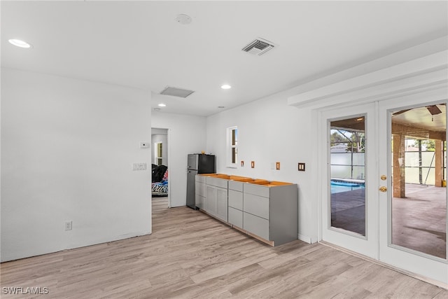 interior space featuring light hardwood / wood-style floors, stainless steel refrigerator, and french doors