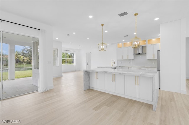 kitchen with backsplash, hanging light fixtures, light hardwood / wood-style floors, light stone counters, and white cabinetry