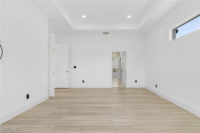 unfurnished room featuring a tray ceiling and light hardwood / wood-style flooring