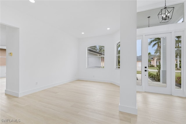 foyer featuring light hardwood / wood-style flooring, a healthy amount of sunlight, and an inviting chandelier