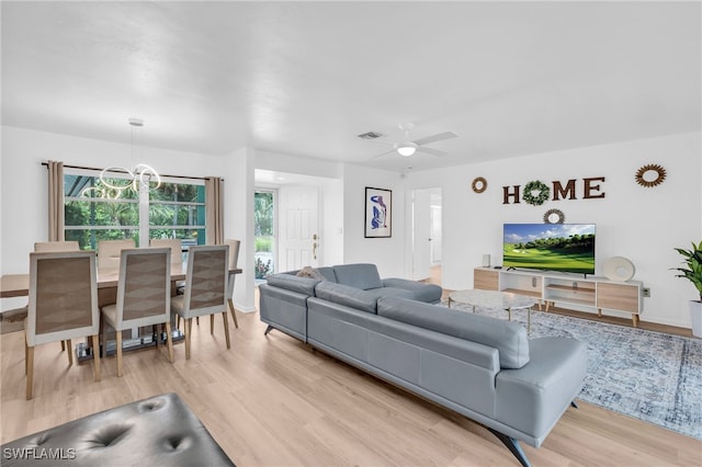 living room with ceiling fan with notable chandelier and light hardwood / wood-style floors