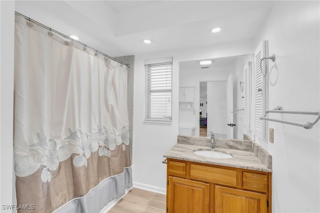 bathroom featuring hardwood / wood-style floors, shower / bathtub combination with curtain, and vanity